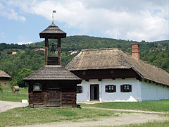 A small wooden belfry from Felsőszenterzsébet, and the house from Baglad is behind it - Szentendre, Maďarsko