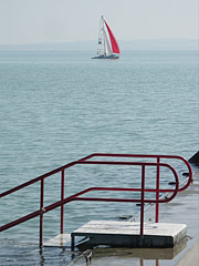 One of the stairs of the beach, as well as in the distance a sailboat can be seen - Balatonfüred, Ungaria