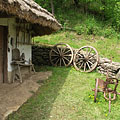 The yard of the folk house with garden tools under the eaves, as well as a plough and two cart wheels - Komlóska, Hungria