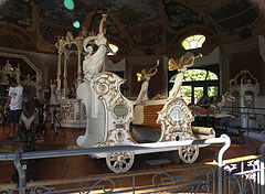 One of the white carriages in the old carousel (merry-go-round), with trumpeting angel or fairy statues - Budapest, Ungheria