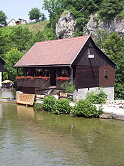 Waterfront old guesthouse in the Rastoke "mill town", in the background a rock wall can be seen, on the other side of the Korana River - Slunj, Croazia