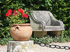 Stone bench and a vase with geranium flowers in the garden of the Széchenyi Mansion of Nagycenk - Nagycenk, Węgry