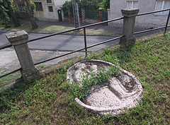 A laid down stone sculpture with a relief in the grass at the St. Michael's Church - Dunakeszi, Унгария