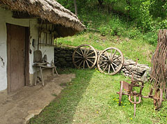 The yard of the folk house with garden tools under the eaves, as well as a plough and two cart wheels - Komlóska, Mađarska