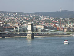 The Buda-side of the Széchenyi Chain Bridge ("Lánchíd"), as well as there are houses on the Buda Hills and a TV-tower on the Hármashatár Hill in the background - Budapešť, Maďarsko