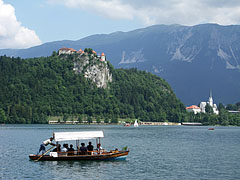 A "pletna", traditional rowing boat on the lake, in th backround it is the Bled Castle and the neo-gothic Parish Church of St. Martin - Bled, Slovenya