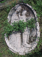 A propably old oval shaped relief in the grass at the St. Michael's church (perhaps a representation of Mary with the child Jesus) - Dunakeszi, Ungaria