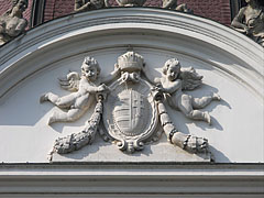 Stone carved coat of arms of Hungary with the crown and two angels or putti, on the main facade of the palace - Gödöllő, Ungaria