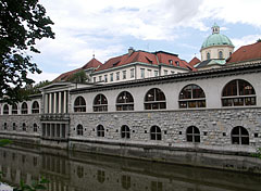 The so-called Plečnik's arcades building complex by the river, and some distance away the roof of the covered market hall ("Pokrita tržnica") and the dome of the Cathedral of St. Nicholas can be seen - Ljubljana, Slovenia