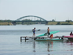 Kids on a pier preparing to go kayaking, and the Árpád Bridge can be seen behind them - Ráckeve, Maďarsko