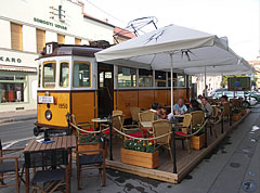 The terrace of the "Blues Café & 7-es megálló" restaurant, including a yellow old tram - Szeged, Macaristan