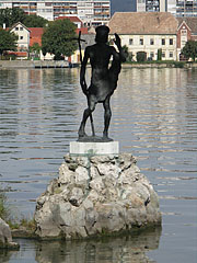 Statue of Saint John the Baptist in lake on a rock, behind the sculpture on the lakeshore the Hamary House can be seen - Tata, Мађарска