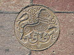 A circular bronze piece of art, a lion figure in the pavement - Esztergom, Unkari