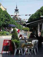 Restaurant terrace on the pedestrian street, and the tower of the Festetics Palace in the background - Keszthely, Hongarije